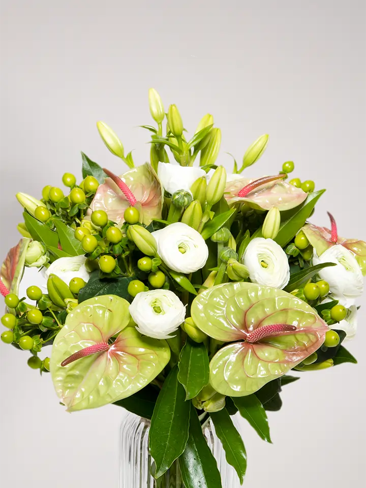 Bouquet di anthurium pistache ranuncoli bianchi e bacche verdi close up